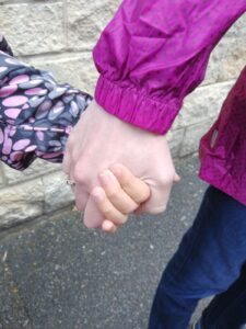 An adult and a child's hands clasped together
